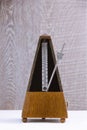 Old metronome in brown wood in motion on grey wooden background Royalty Free Stock Photo