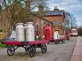 Old milk churns on a trolley at Hadlow Road Railway Station in Wirral, England, UK. A Grade 2 listed heritage museum