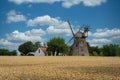 Old mill with a farm in the background and a crop field in front in Svaneke, Denmark.