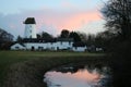 Old mill, houses, reflection in water near sunset Royalty Free Stock Photo