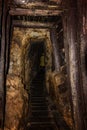 Old mine shaft with wooden timbering and person dressed in a mining mantel in background Royalty Free Stock Photo