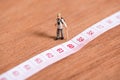 Old miniature traveler with 60th number of age on measuring tape Royalty Free Stock Photo