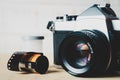 Old 35mm SLR film camera and a roll of film on wooden background. Flim photography concept Royalty Free Stock Photo