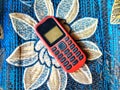 Old Mobile Phone with Texting or SMS Button Keyboard or Keypad on Colorful Flowery Fabric Background Royalty Free Stock Photo