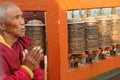 Old monk reads mantra near praying mills