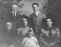 Vintage monochrome studio photograph of a family of three generations dating to the early 1900s, Edwardian era.