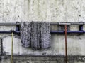 Old mop lay on the steel rail to dry, Old faucet and old rubber hose, Old cement wall background Royalty Free Stock Photo