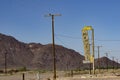 Old motel sign along highway on part Route 66 standing among parallel lines of low mountain range and power poles Royalty Free Stock Photo