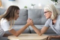 Old mother and grown daughter arm wrestling having family fight Royalty Free Stock Photo