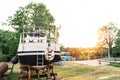 Old motor boat with two lifebuoys is moored in an outdoor workshop under repair