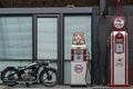 An old motorcycle and two retro gasoline pumps.