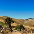 An old mountain road with an old fence, a tree on the side and mountain peaks in the distance. Bjelasnica Mountain Royalty Free Stock Photo