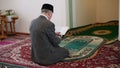 An old mullah praying with the Koran in his hands