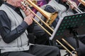 Old musican dressed in men`s classic vest playing on a trombone in an orchestra, music stand behind him. Royalty Free Stock Photo