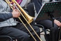 Old musican dressed in men`s classic vest playing on a trombone in an orchestra, music stand behind him Royalty Free Stock Photo