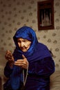 An old Muslim grandmother prays against the background of prayer with a rosary in her hands