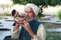 Old muslim man with turban blowing a trumpet