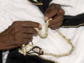 Old Muslim man wearing a black and white traditional garment and holding a rosary in his hands