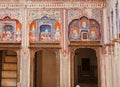 Old naive fresco with portraits of people, patterns on historical home walls of India