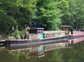 Old narrow boats reflected in the water and surrounded by trees on the rochdale canal in hebden bridge west yorkshire Royalty Free Stock Photo