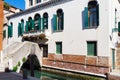 Old narrow canal with a small bridge to white house, Venice, Italy. Traditional flooded street or alley of Venice