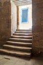 Old narrow dark passage and staircase leading to outdoor small lobby with blue wooden windows Royalty Free Stock Photo