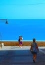 Old narrow street with people and panoramic view on the port and sea in front of Sciacca, Sicily, Italy