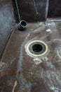 Old nasty and dirty water sink with drain hole and plug. Close up wide angle shot, no people Royalty Free Stock Photo