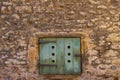 Old natural stone wall with closed ancient wooden shutters