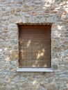 Old natural wooden roller shutter on stone wall. Window with closed shutter on old stone facade Royalty Free Stock Photo