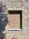 Old natural wooden roller shutter on stone wall. Window with closed shutter on old stone facade Royalty Free Stock Photo