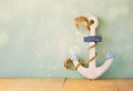 Old nautical anchor on wooden table over wooden aqua background and glitter overlay Royalty Free Stock Photo