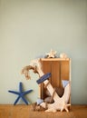 Old nautical wood anchor and shells on wooden table over wooden aqua background