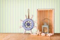 Old nautical wood wheel, anchor and shells on wooden table over retro background Royalty Free Stock Photo
