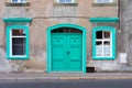 Old neglected abandoned white townhouse with green doors and windows