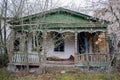 The old, neglected, lordly house and porch among the trees. Texture of old cracked wood painted green.