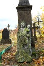 Old neglected, mutilated figures of saints and crosses on graves.