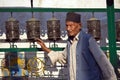 Old nepali man rotating buddhist prayer wheels in Nepal