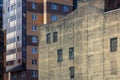 Old and new building. In the foreground is an abandoned house with broken windows and a brick wall covered with mesh.