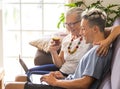 The old and new generation of millennials share the same laptop while having fun. Grandson teaches grandmother how to surf the