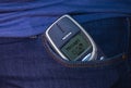 Old Nokia cell phone with a message on the screen sticks out of blue jeans pocket Royalty Free Stock Photo