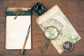 Old notebook, compass, map, pen and inkwell, magnifying glass on wooden background Royalty Free Stock Photo