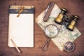 Old notebook, compass, map, vintage binoculars, pencil, knife, magnifying glass on wooden desk background Royalty Free Stock Photo