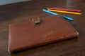 Old notebook with leather cover on a wooden table and colorful pencils Royalty Free Stock Photo