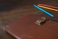 Old notebook with leather cover on a wooden table and colorful pencils Royalty Free Stock Photo