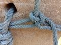 Old nylon ship ropes tied to knot bound around cement electrical post on ground flooring closeup.