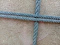 Old nylon ship ropes tied to knot bound around cement electrical post on ground flooring closeup.