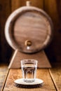 Old oak barrel and glass of high quality distilled alcohol. Brazilian silver cachaÃÂ§a, called pinga, vodka, white rum, liqueur, Royalty Free Stock Photo