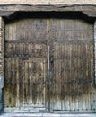 Old oak wood door with reinforcement nails, small door and iron knocker, with a wooden beam on top. It served for the passage of c Royalty Free Stock Photo