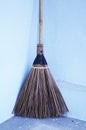 Old obsolete broom or besom leaning on the gray wall